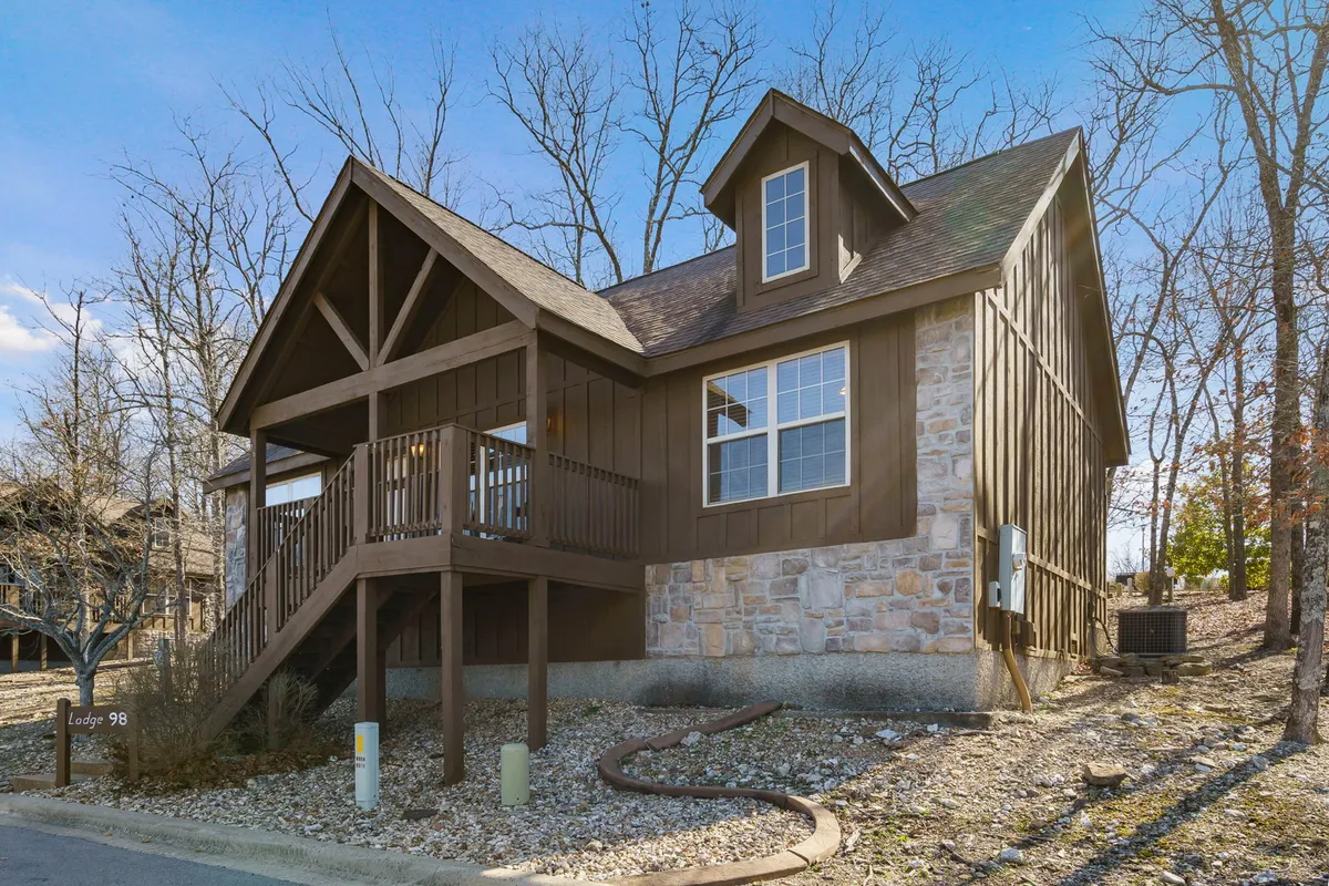 An exterior shot of the front porch featuring sturdy wooden beams and a stone wall, with comfortable seating positioned to take in expansive views and the peaceful ambiance of the Ozarks.