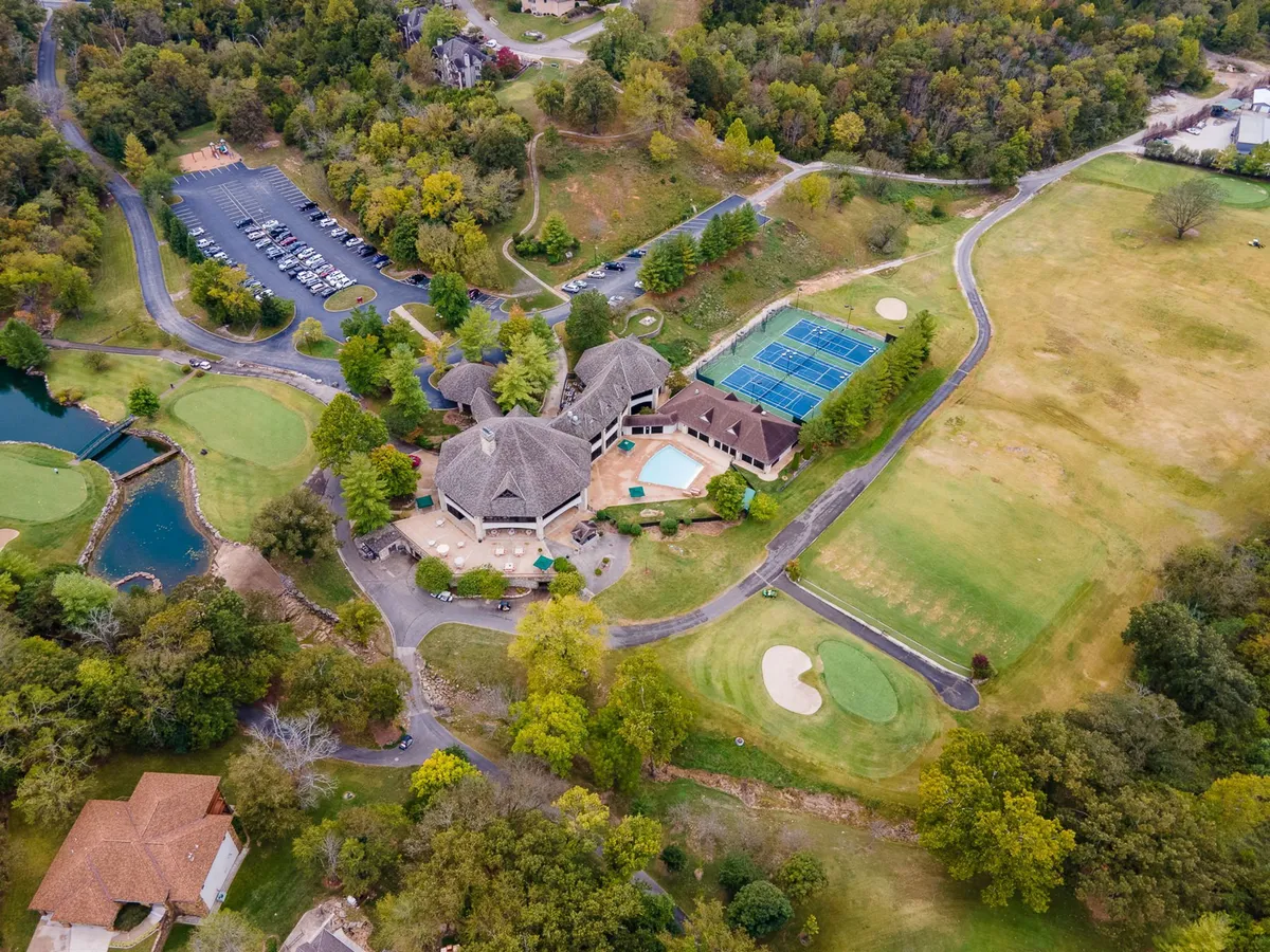 This image captures an expansive view of the resort's key amenities: the championship golf course, a sparkling swimming pool, tennis courts, and the welcoming clubhouse, all surrounded by lush greenery and bathed in sunlight. Guests can visualize themselves engaging in a range of leisurely activities, from swimming and golfing to socializing outdoors.