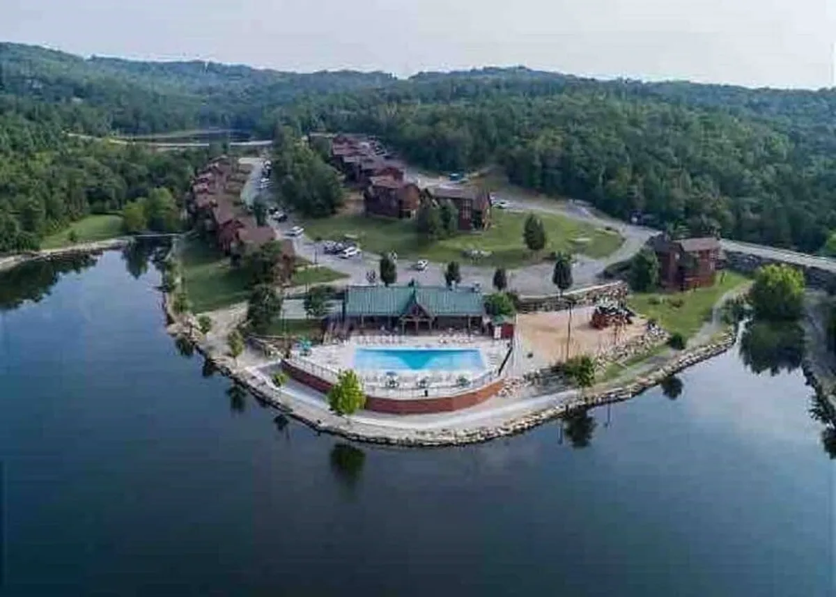 A sparkling swimming pool with lounge areas, set against lush greenery and a waterfront view. The adjacent clubhouse and natural surroundings offer a relaxing and social atmosphere for families.